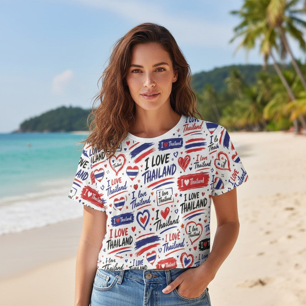 THAILISH.SHOP white polyester crop tee with all-over print of "I Love Thailand" text, hearts, and Thai flag stripes in red, white, and blue.